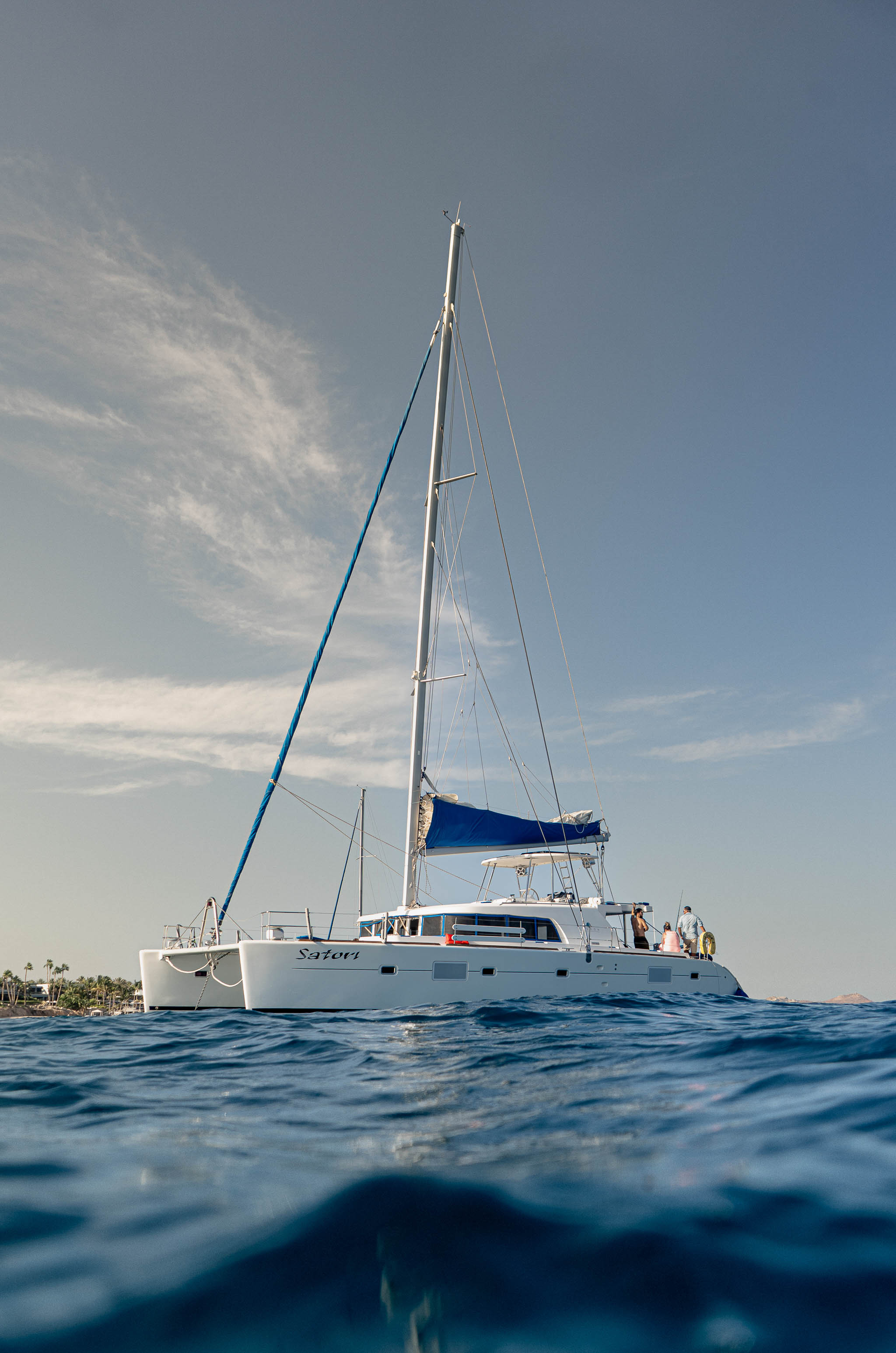 Luxury catamaran sailing along the palm-lined Los Cabos coastline